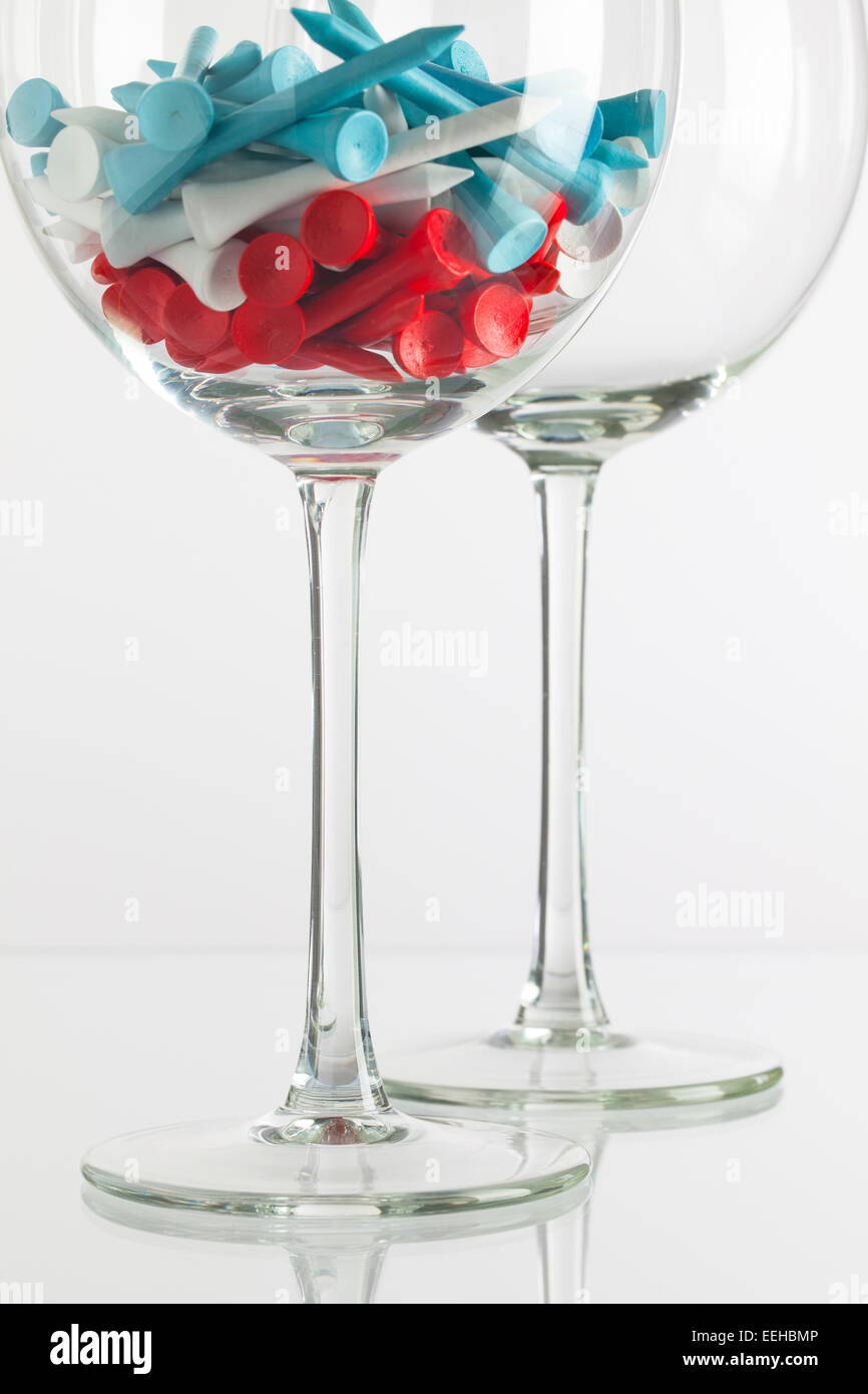 Due bicchieri di vino e attrezzature da golf sulla scrivania in vetro Foto Stock