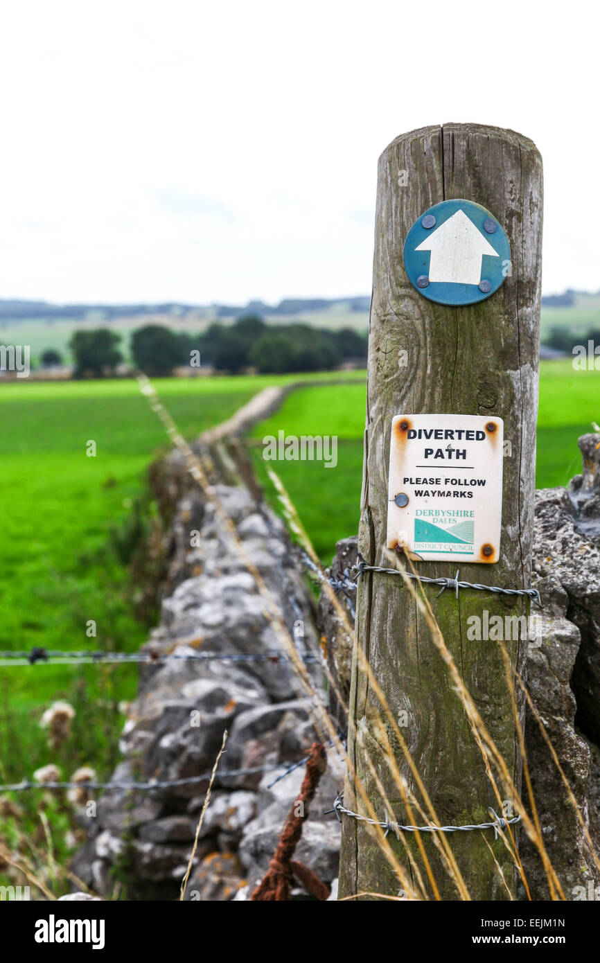 Un segno in un campo con muri in pietra a secco dicendo deviato il percorso si prega di seguire waymarkers Derbyshire Dales consiglio del distretto Foto Stock
