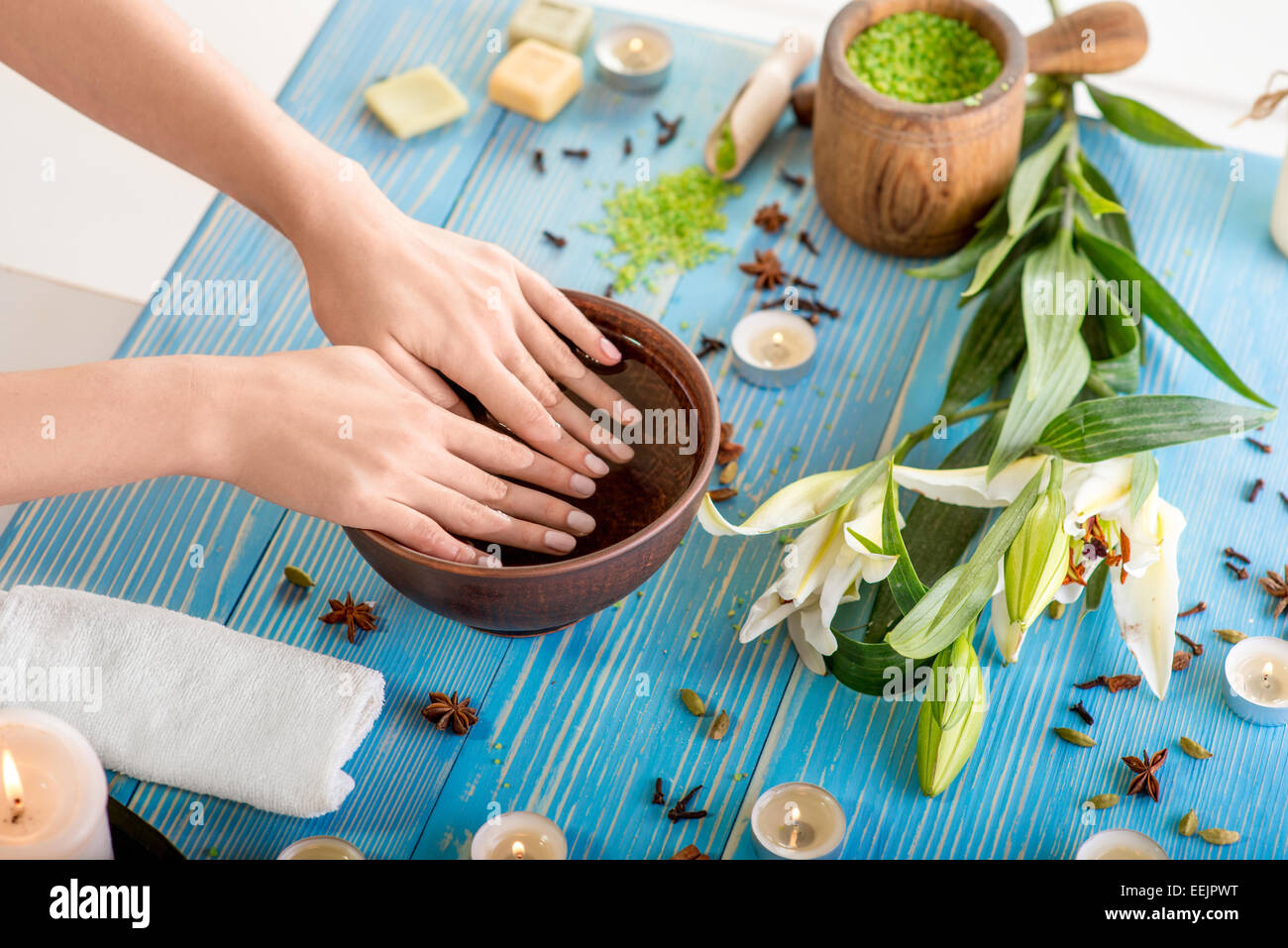 Ammollo unghie nel bagno con acqua sul tavolo di legno con spa roba in background Foto Stock
