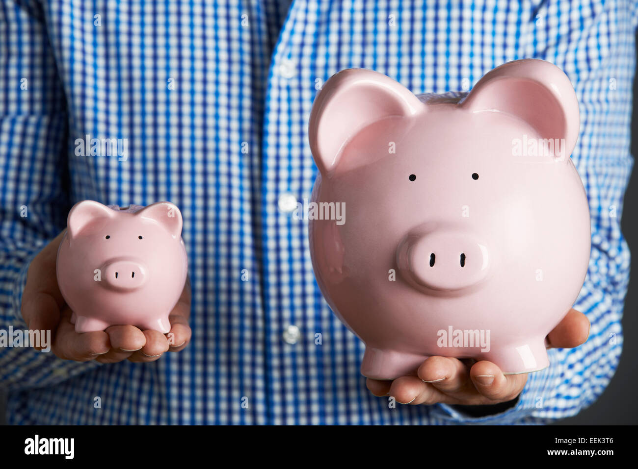 Uomo con grandi e piccole Salvadanaio Foto Stock