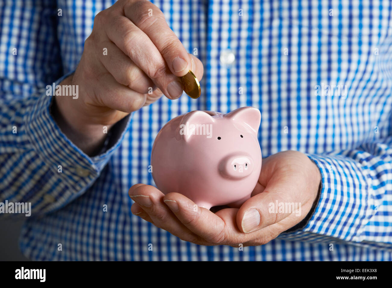 Uomo di mettere moneta nel salvadanaio Foto Stock