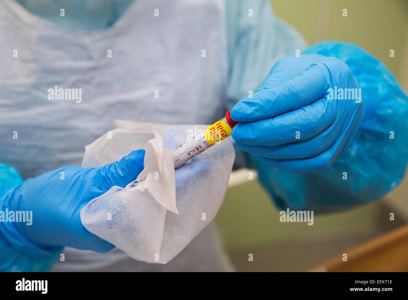 Il virus di Ebola patologia campione di sangue essendo trattenuto dal lavoratore di cura di salute in abbigliamento protettivo Foto Stock