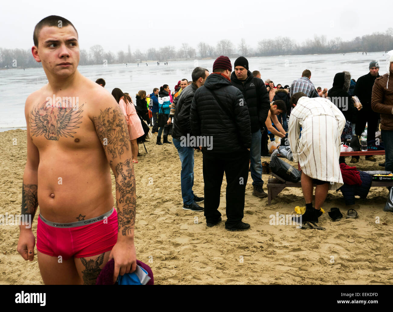 Kiev, Ucraina. 19 gennaio, 2015. Giovane uomo in un costume da bagno rivestito di costo tra i credenti sulle rive del Dniepr. -- 19 gennaio, 2015, Kiev, Ucraina, grande cristiano di vacanza epifania. Una delle principali tradizioni della celebrazione è il nuoto in Giordania (il cosiddetto consacrato sacerdote il foro). L'inverno è stato insolitamente mite in Ucraina e nuoto appena tenuto sulla spiaggia. Chiesa ucraina del Patriarcato di Mosca tradizionalmente celebrata in Obolon. Credito: Igor Golovnov/Alamy Live News Foto Stock