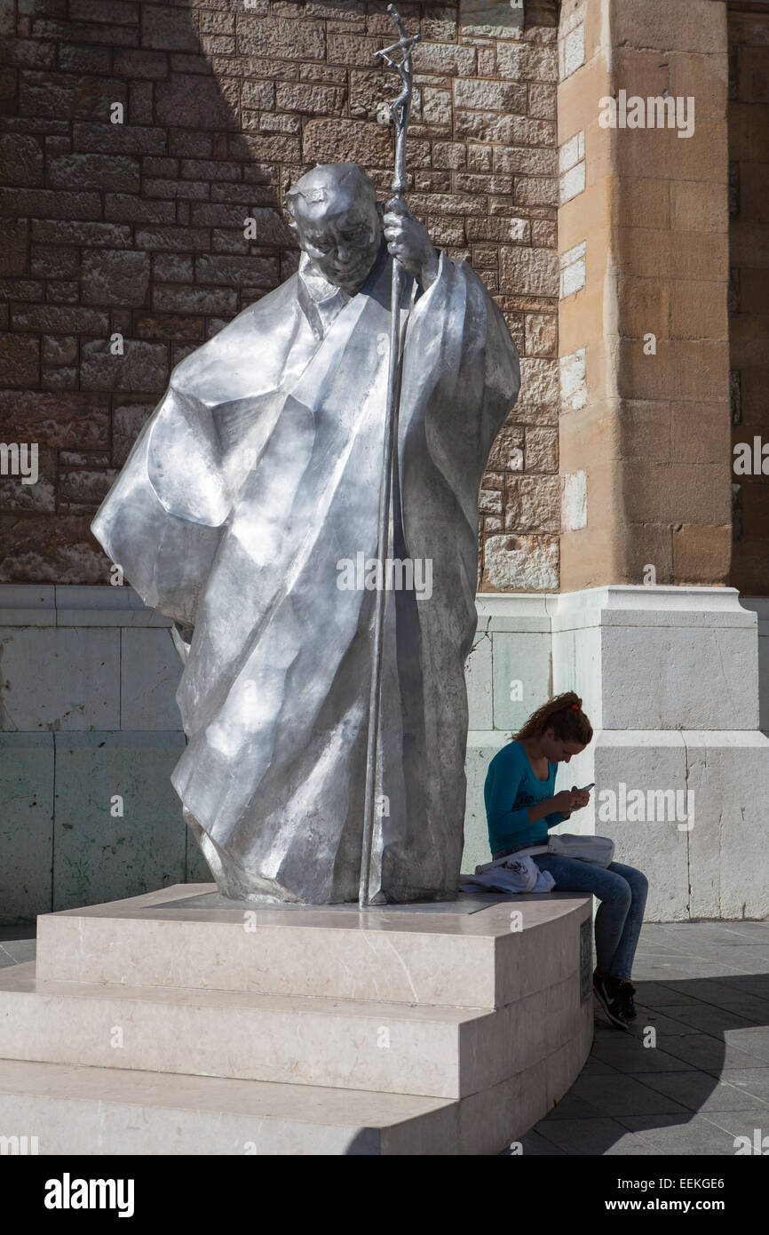 Una ragazza seduta alla base del Karol Wojtyla statua realizzata da Sarajevo Nato scultore Hrvoje Uremovic davanti a Gesù Sacre Foto Stock