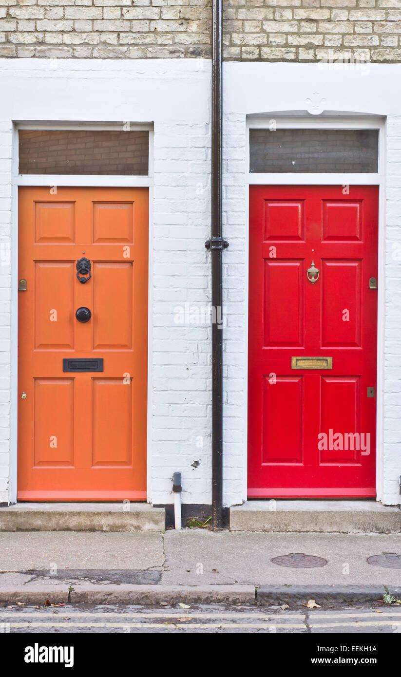 Rosso e arancio porte anteriori sulla adiacente case a schiera nel Regno Unito Foto Stock