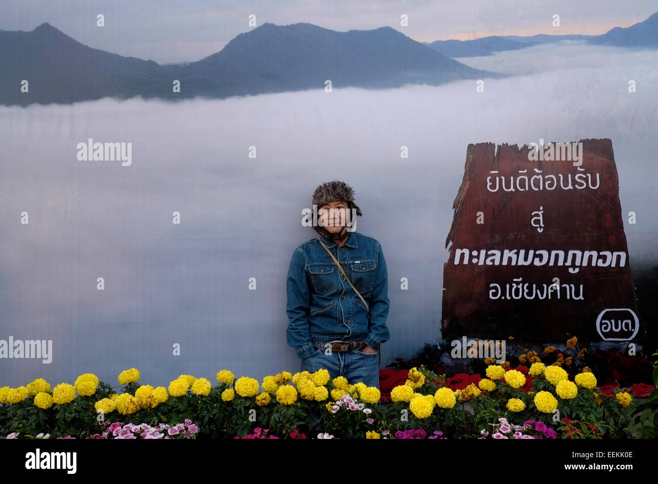 Local Thai visitatore in posa di fronte a grandi poster raffigurante il mare di nebbia nella parte superiore dell'unità PHU Tok mountain si trova al centro di Bueng Kan provincia nell'estremità nord-orientale di Isan, a nord-est della Thailandia. Foto Stock