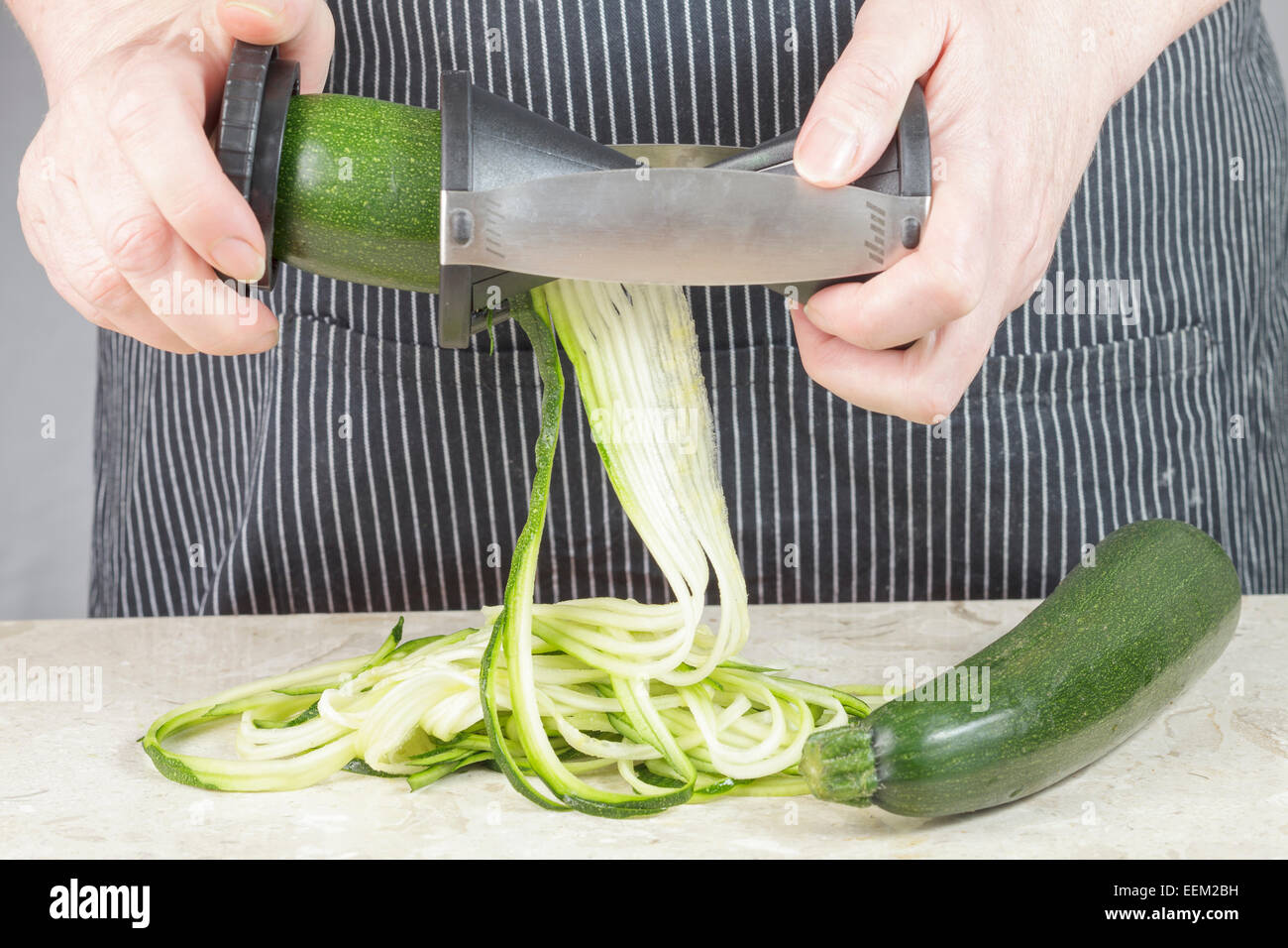 Utilizzando una spirale vegetale maker per rendere la zucchina tagliatelle o zoodles Foto Stock