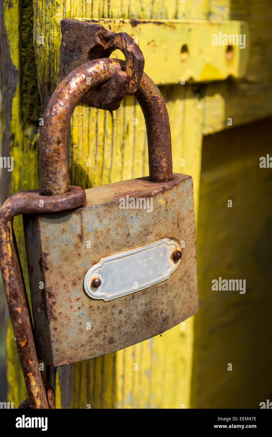 Rusty serratura con scrocco attaccati ad un giallo porta di legno, close-up Foto Stock