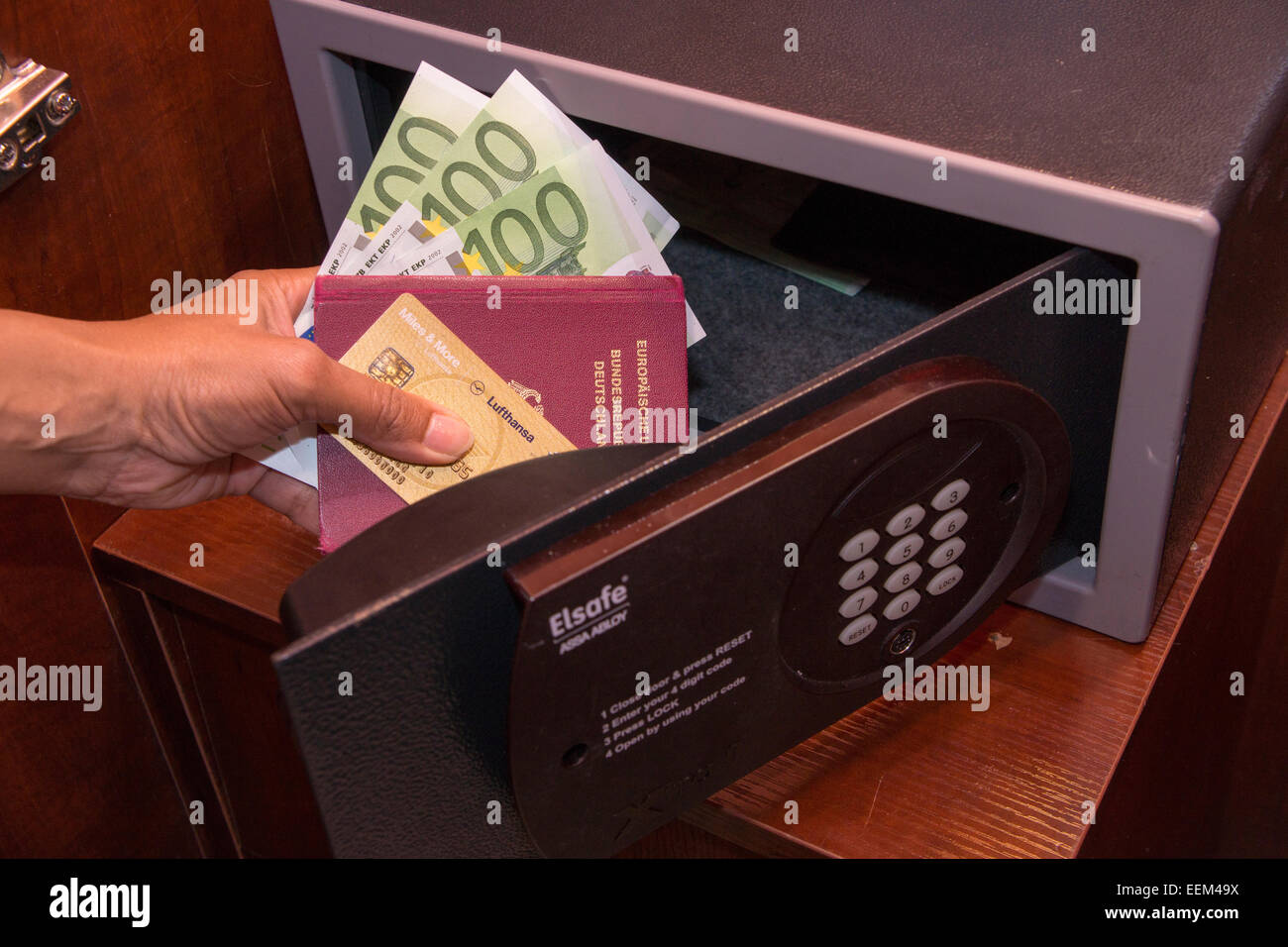 Aprire cassaforte, mano che tiene la carta di credito, passaporto e contanti, in una camera di hotel Foto Stock