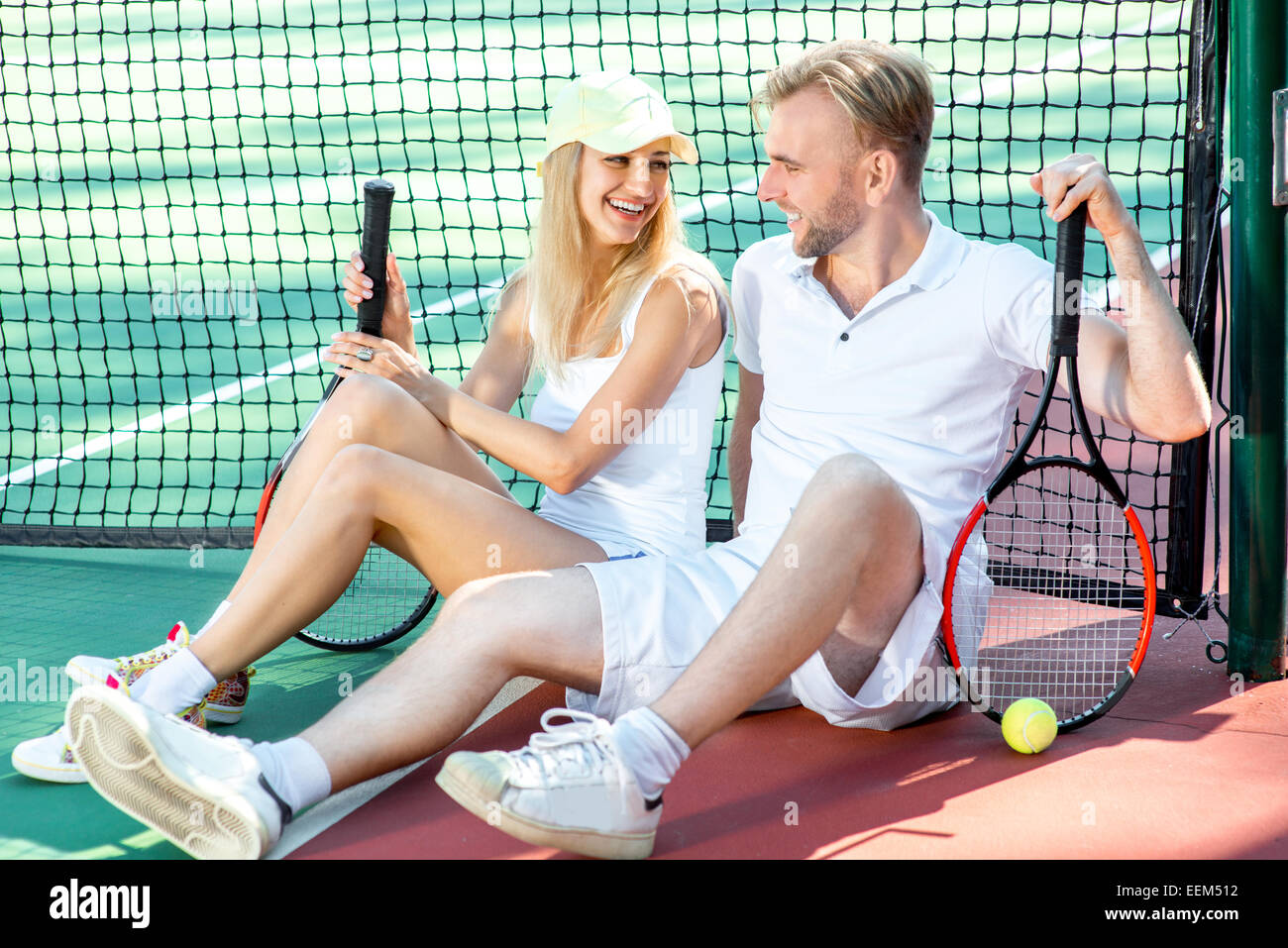 I giovani coniugi giocando a tennis in bianco sportwear sul campo da tennis esterno in estate Foto Stock
