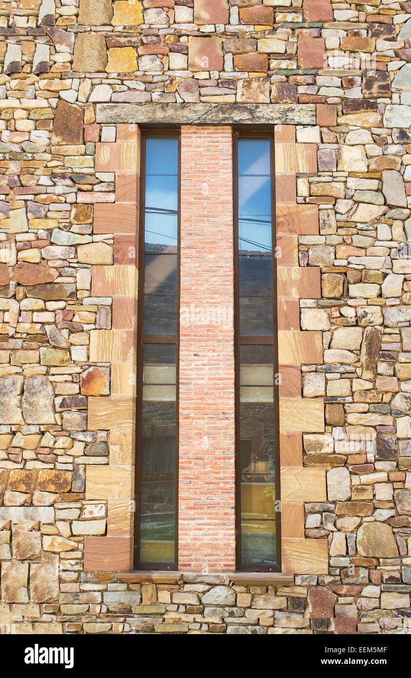 Long , finestre verticali separate da uno strato di mattoni decorativi su una pietra della parete placcato Foto Stock