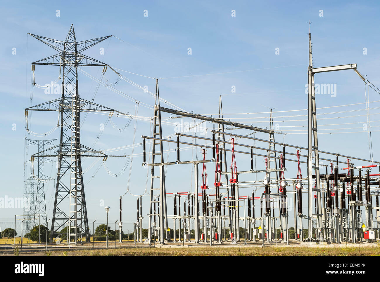 Righe di linee elettriche ad alta tensione che trasportano elettricità da una vicina stazione elettrica Foto Stock