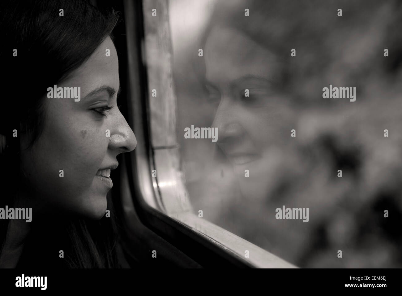 Donna seduta su un treno guardando fuori della finestra Foto Stock