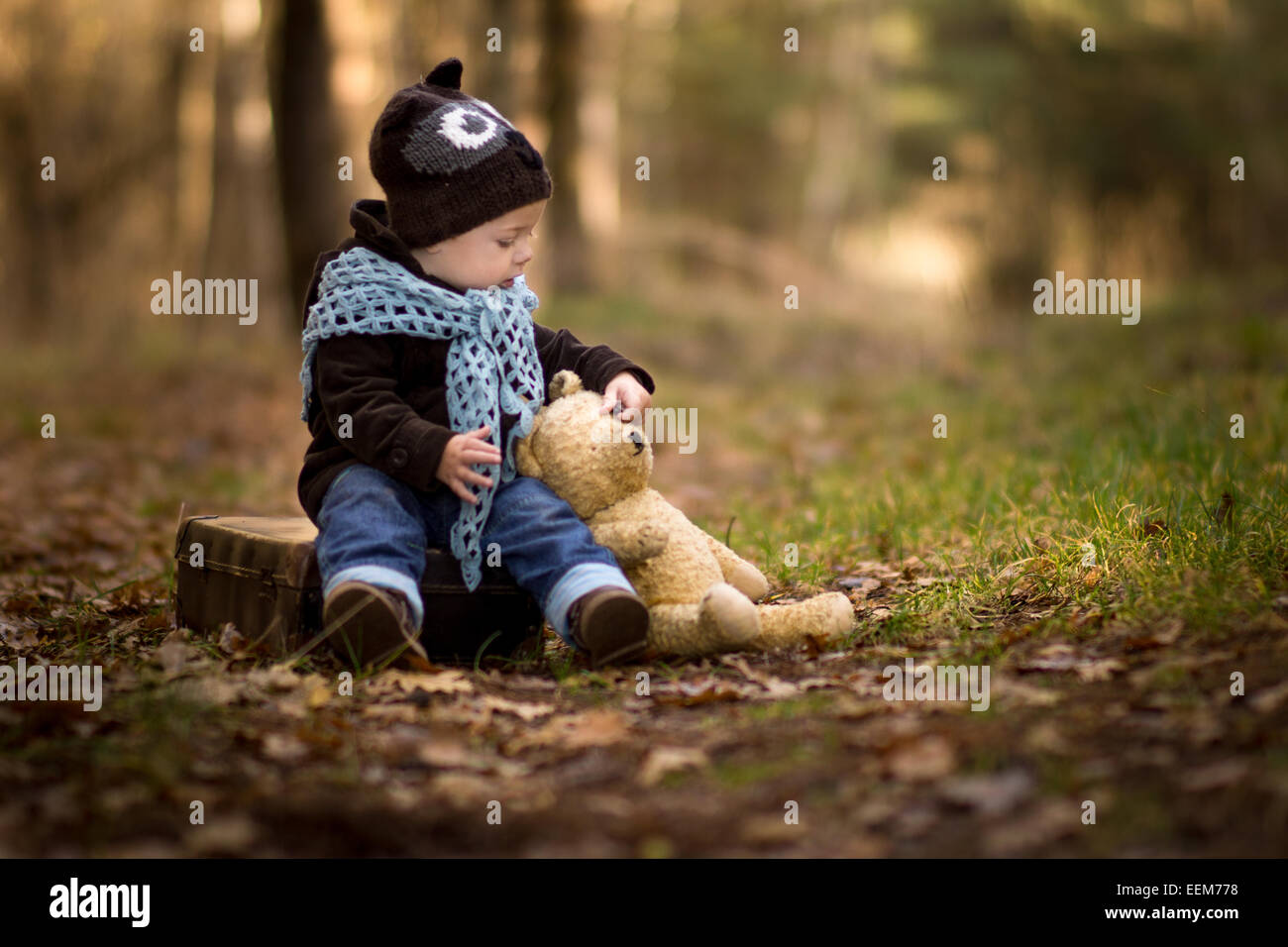 Ritratto di bambino seduto nella foresta con il suo orsacchiotto di peluche Foto Stock