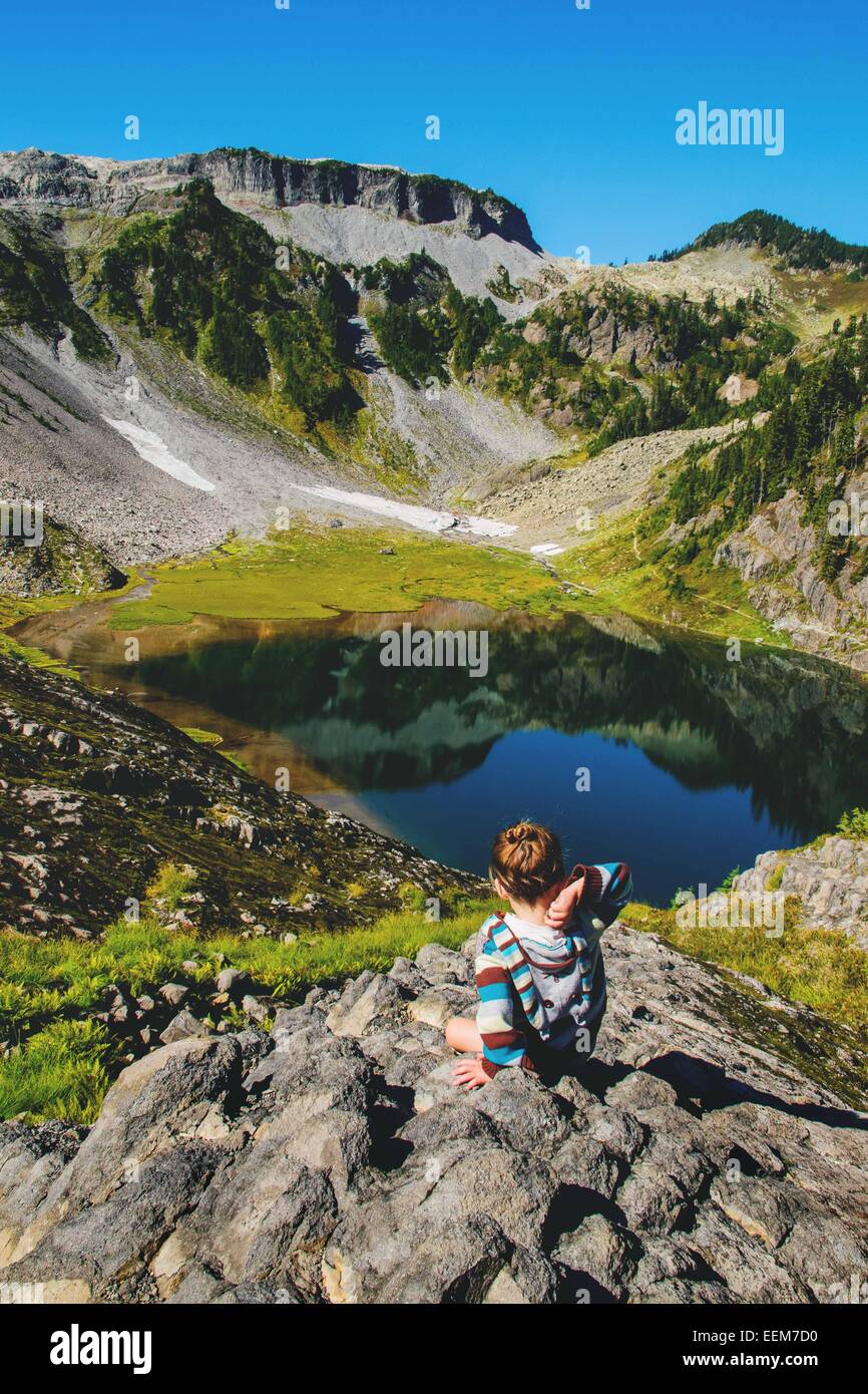 Ragazza che getta una roccia in un lago alpino, Stati Uniti Foto Stock