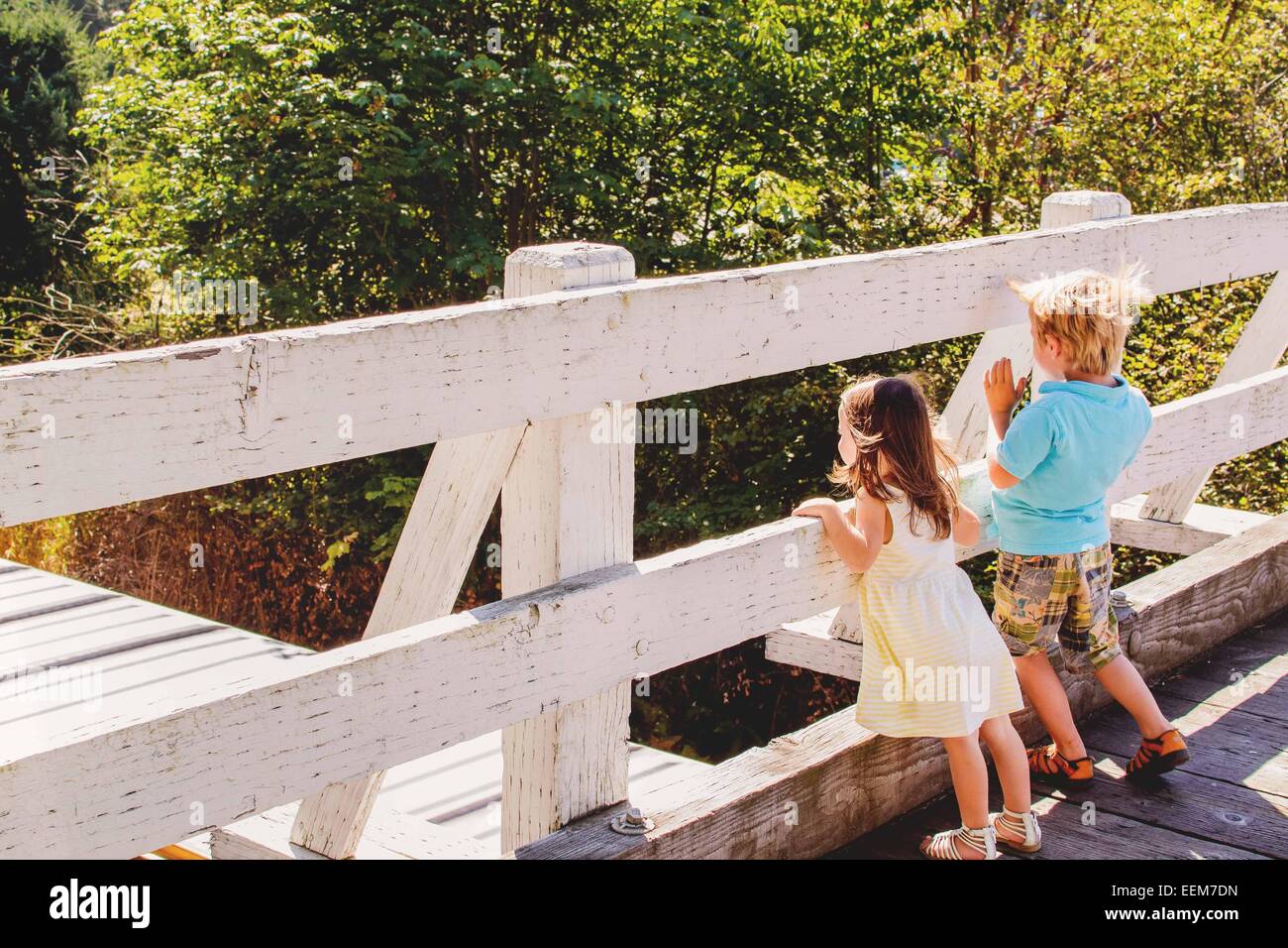 Due bambini che guardano il treno che passa sotto un ponte Foto Stock