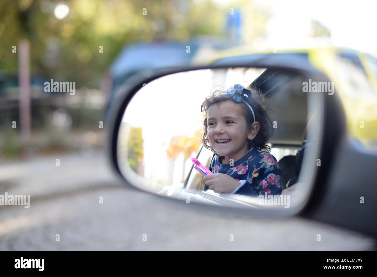 La ragazza (4-5) godendo di viaggio in auto e cercando in specchietto retrovisore Foto Stock