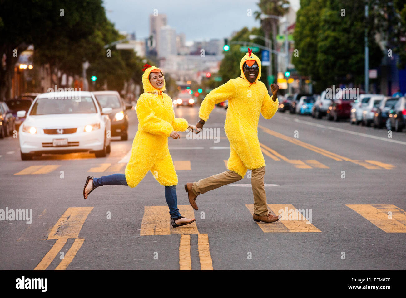 Matura in costumi di pollo attraversando via della città Foto Stock