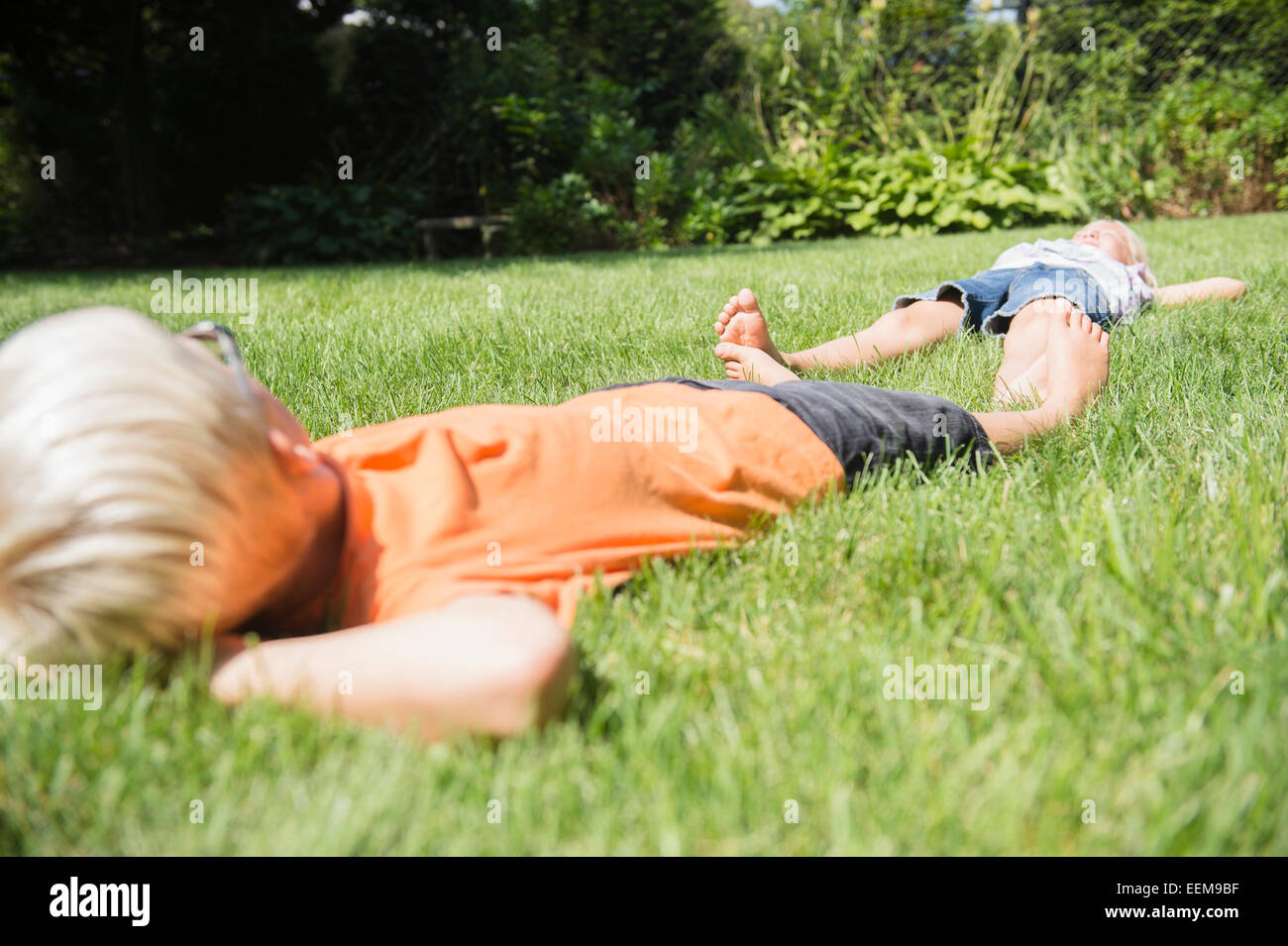 Bambini caucasici posa sul prato in cortile Foto Stock