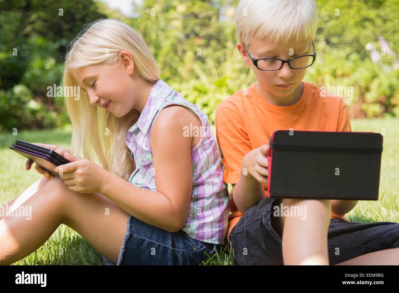 Bambini caucasici utilizzando compresse digitale in cortile Foto Stock
