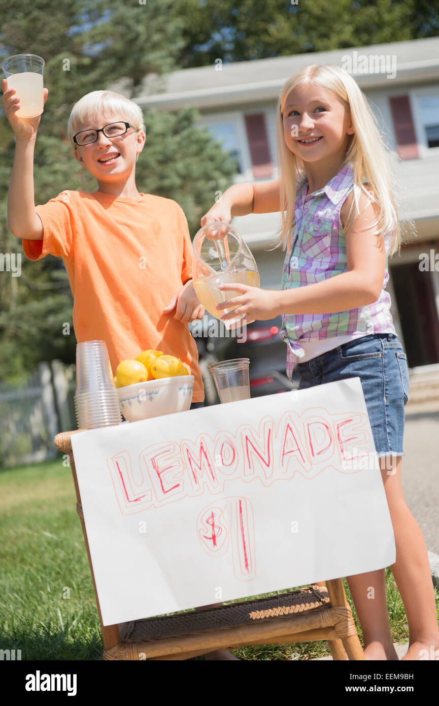 Bambini caucasici vendendo limonata in cortile anteriore Foto Stock