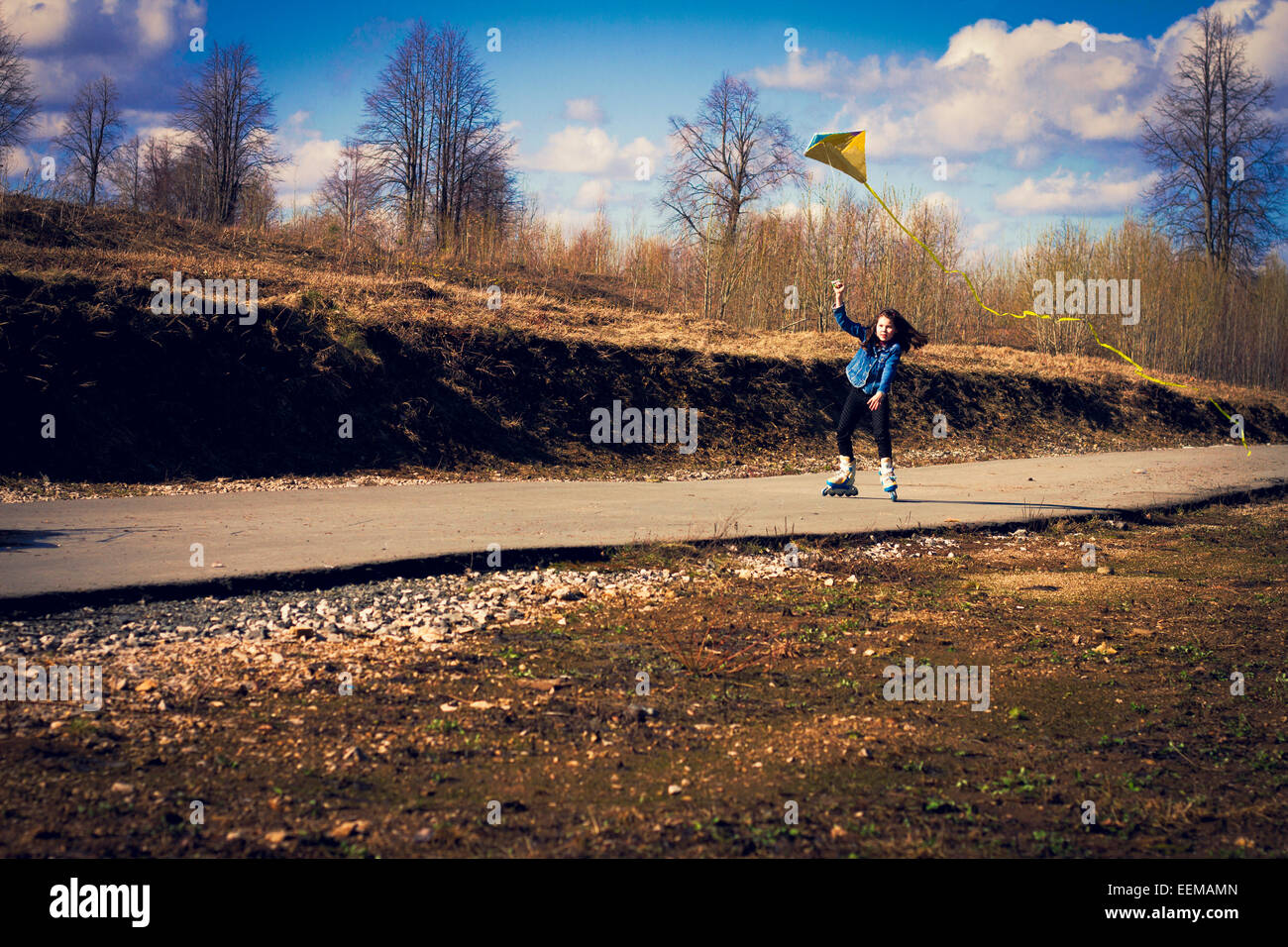 Ragazza caucasica su pattini inline aquilone volante sulla strada rurale Foto Stock