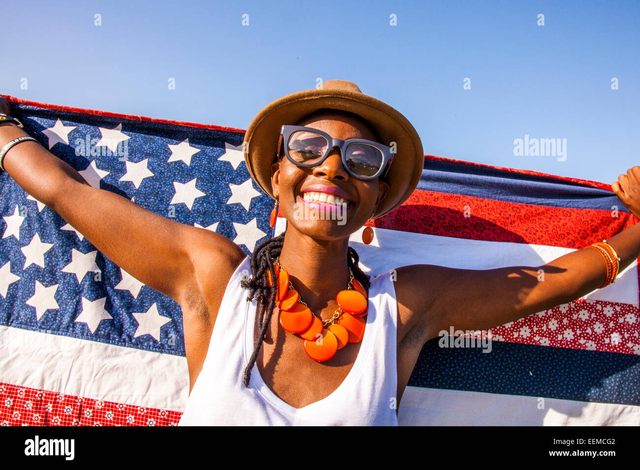 Nero donna holding bandiera americana sotto il cielo blu Foto Stock