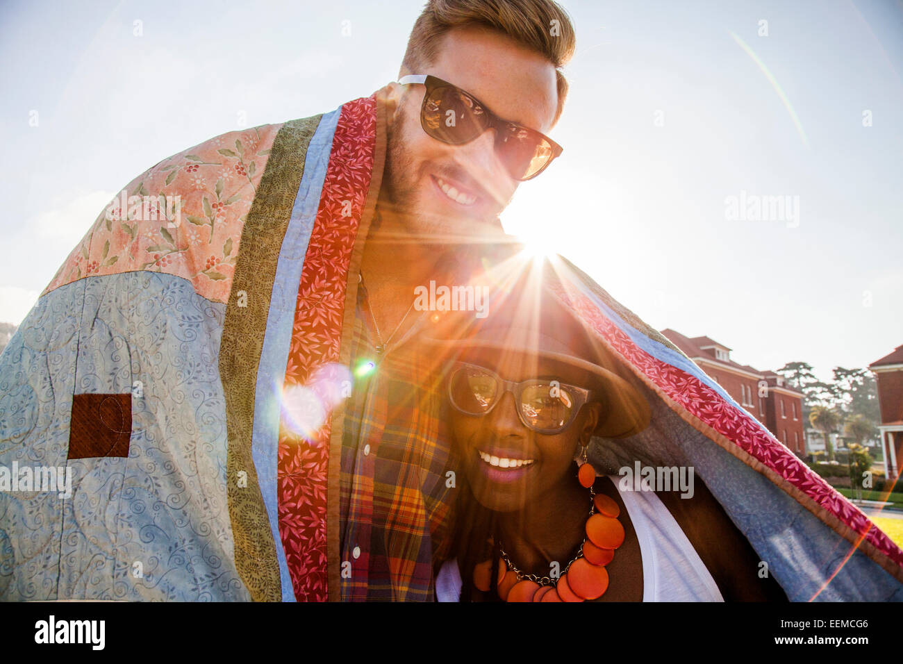 Giovane avvolto in una coperta a sorridere all'aperto Foto Stock