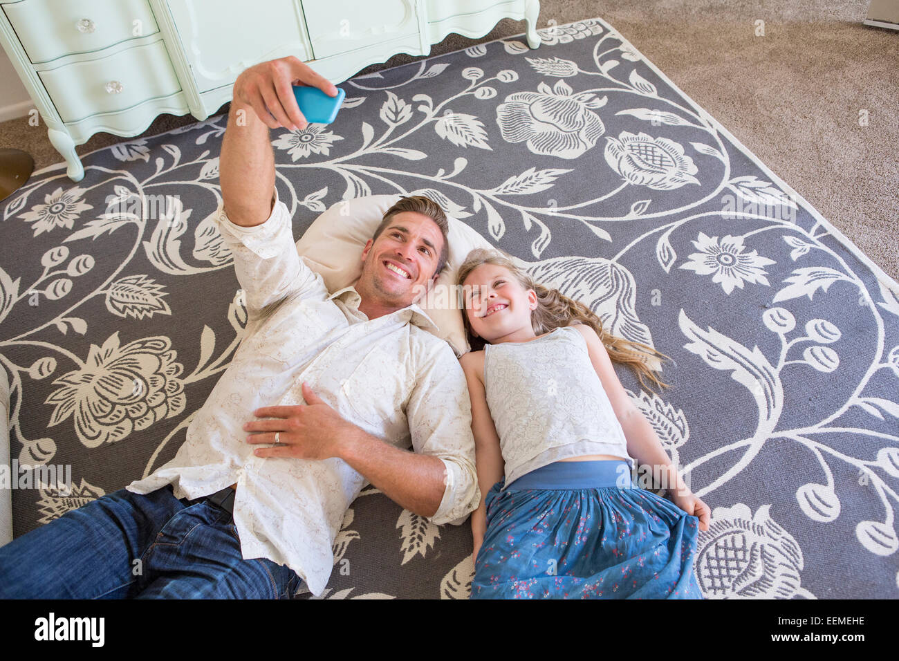 Caucasian padre e figlia tenendo cellulare selfie sul pavimento Foto Stock