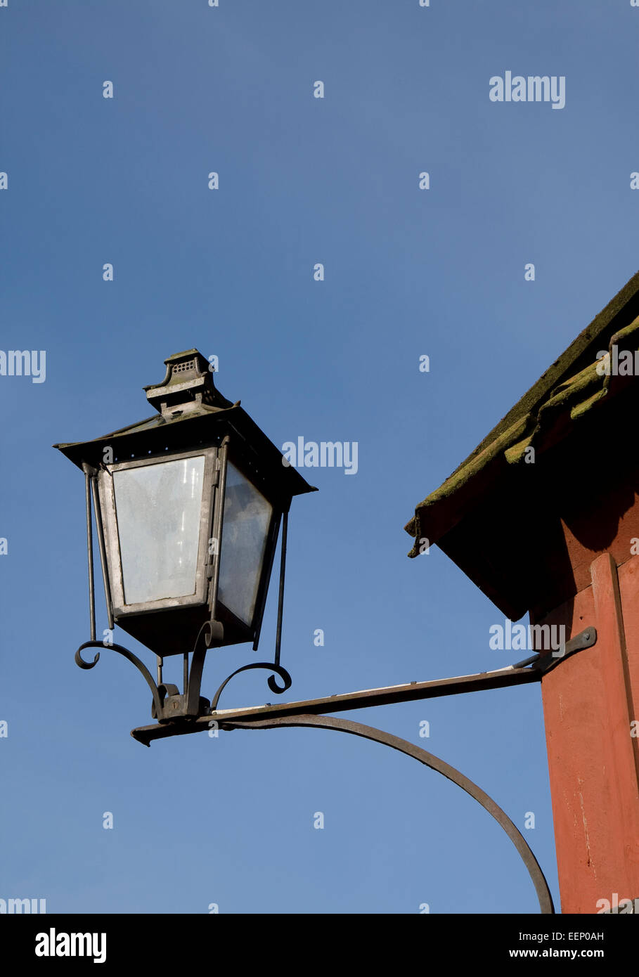 Lampada da esterni sulla parete rossa contro il cielo blu Foto Stock