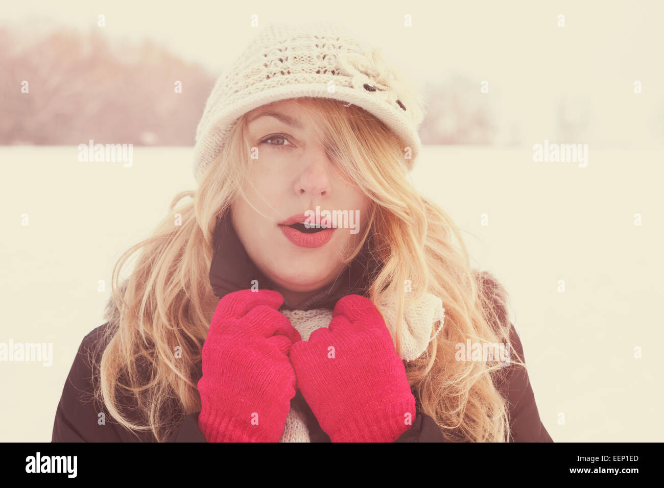 Inverno donna in foto della neve, cercando e soffia il respiro in telecamera fuori in inverno freddo giorno d'annata. Ritratto femminile caucasica mod Foto Stock