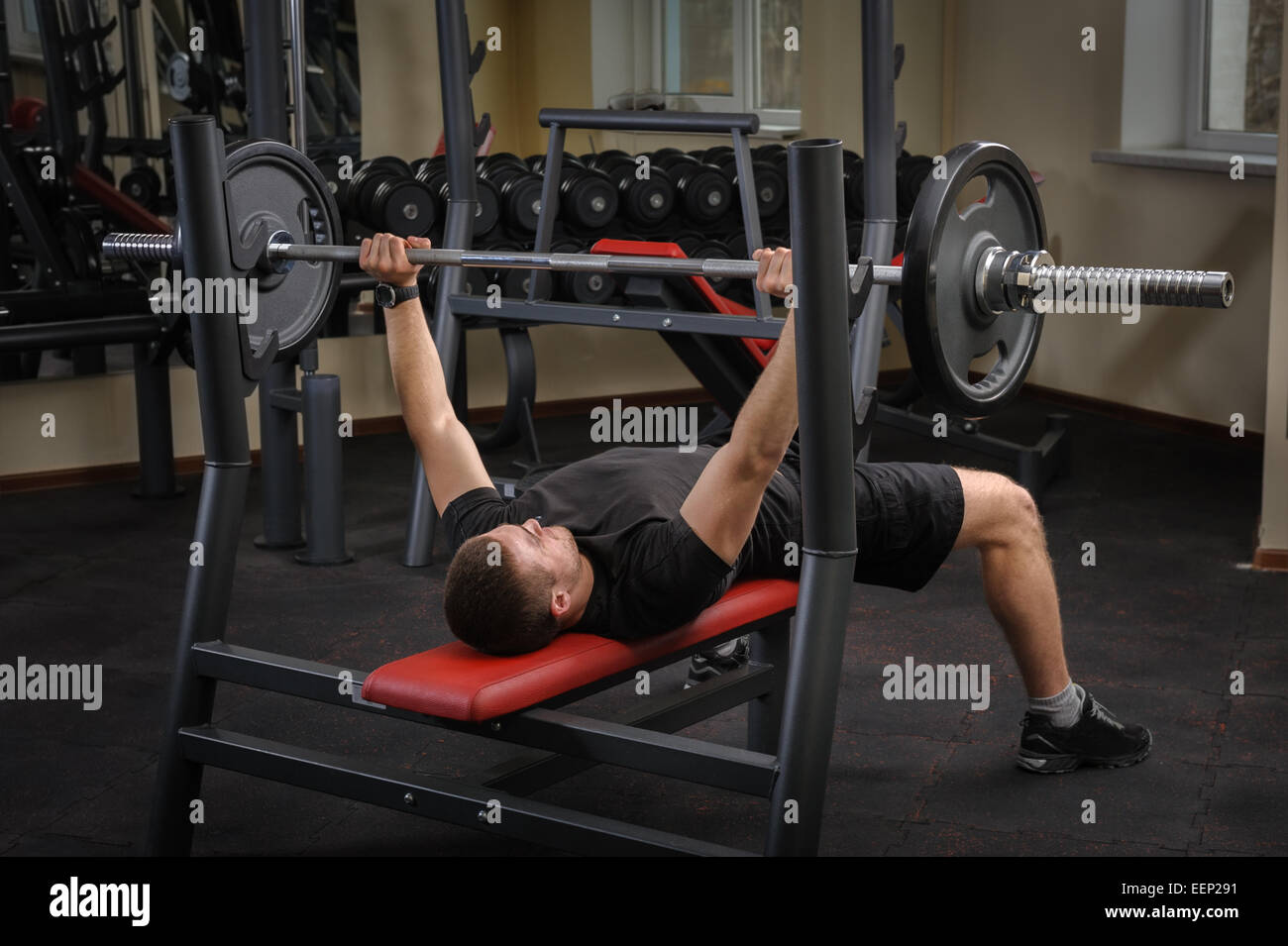 Giovane uomo facendo la pressa da banco allenamento in palestra Foto Stock