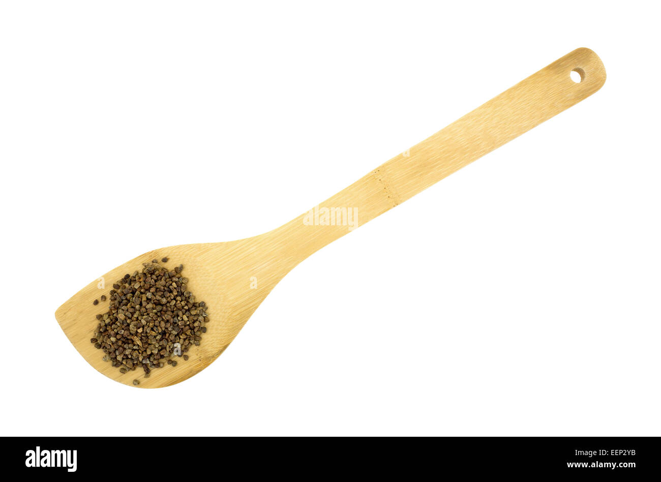 Un cucchiaio di legno con una porzione di semi di cardamomo su uno sfondo bianco. Foto Stock