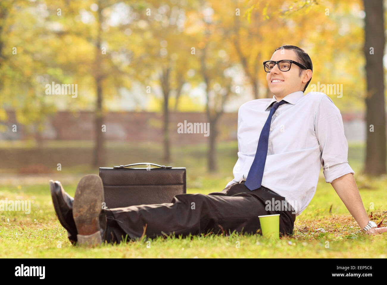 Imprenditore rilassarsi seduti sul prato in posizione di parcheggio Foto Stock