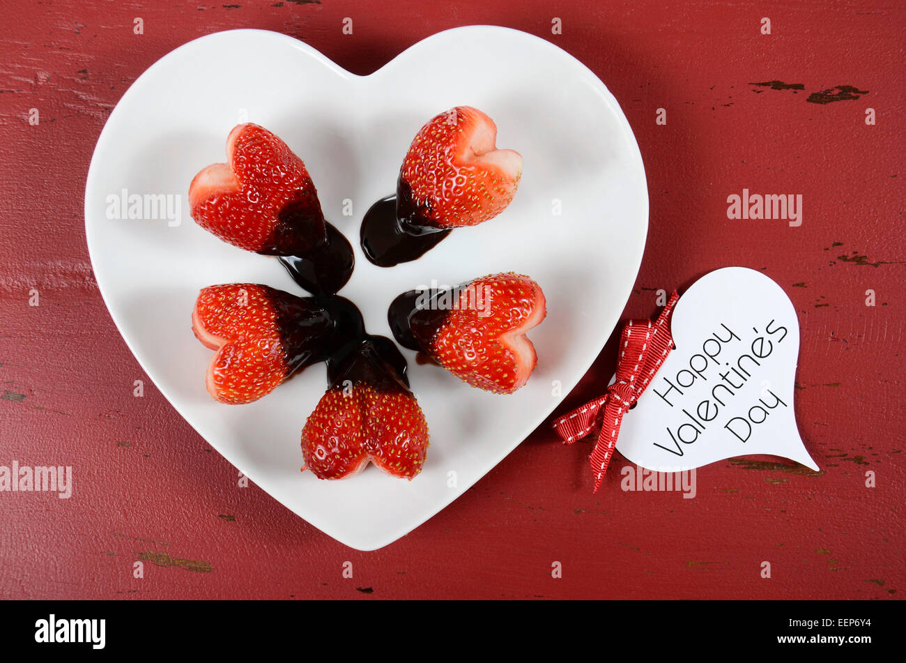 Felice il giorno di San Valentino immerso al cioccolato a forma di cuore di fragole a forma di cuore la piastra di bianco su rosso vintage Sfondo legno, overh Foto Stock