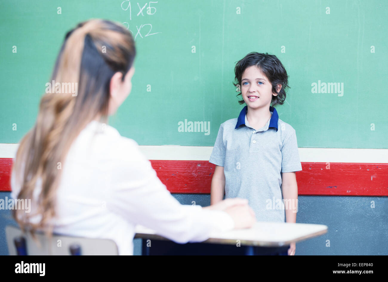 Ragazzo interrogato a scuola nella parte anteriore della lavagna. Foto Stock