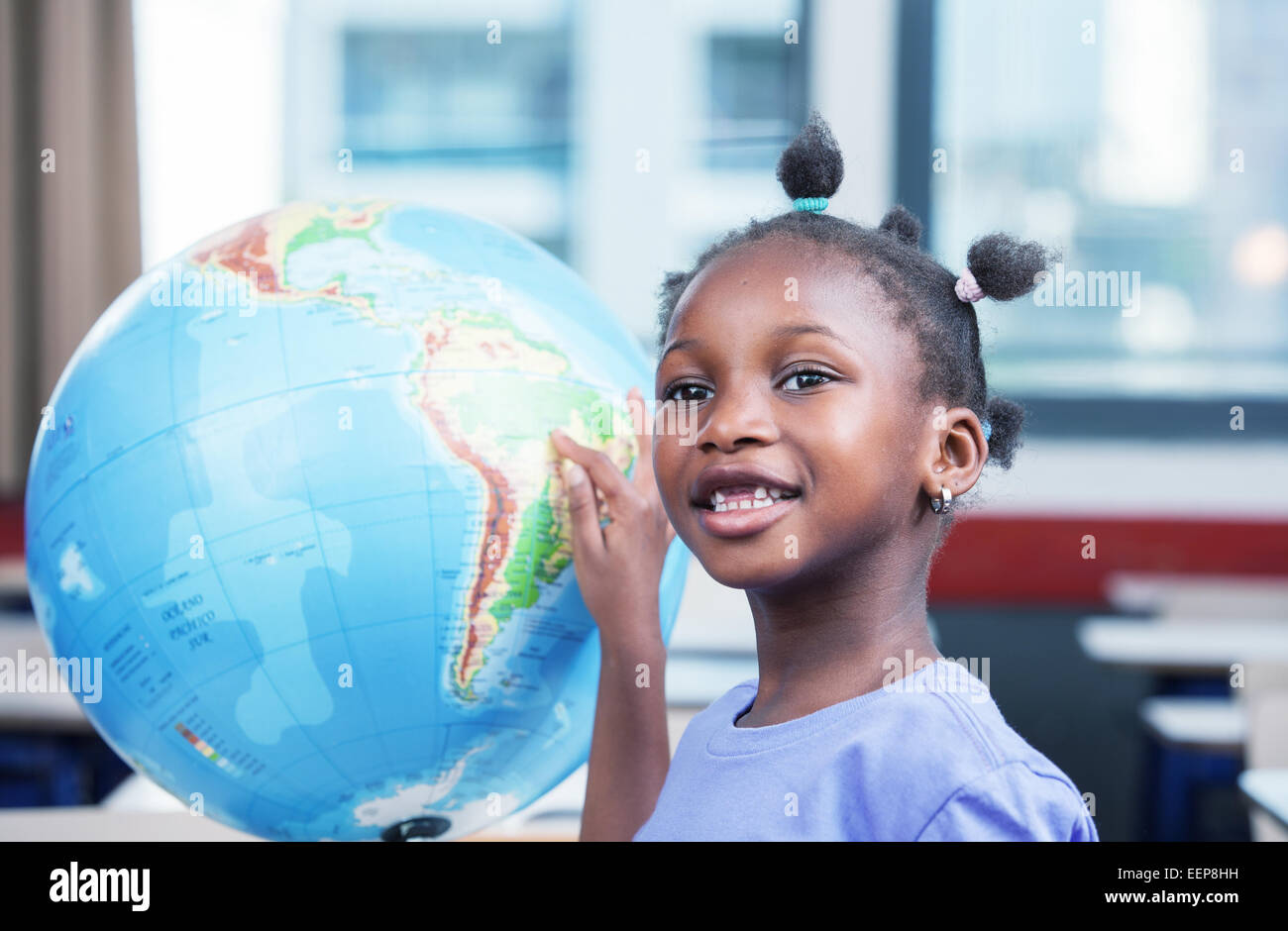 Giovani afro american nero ragazza a scuola sorridente toccando un globo mondo. Foto Stock