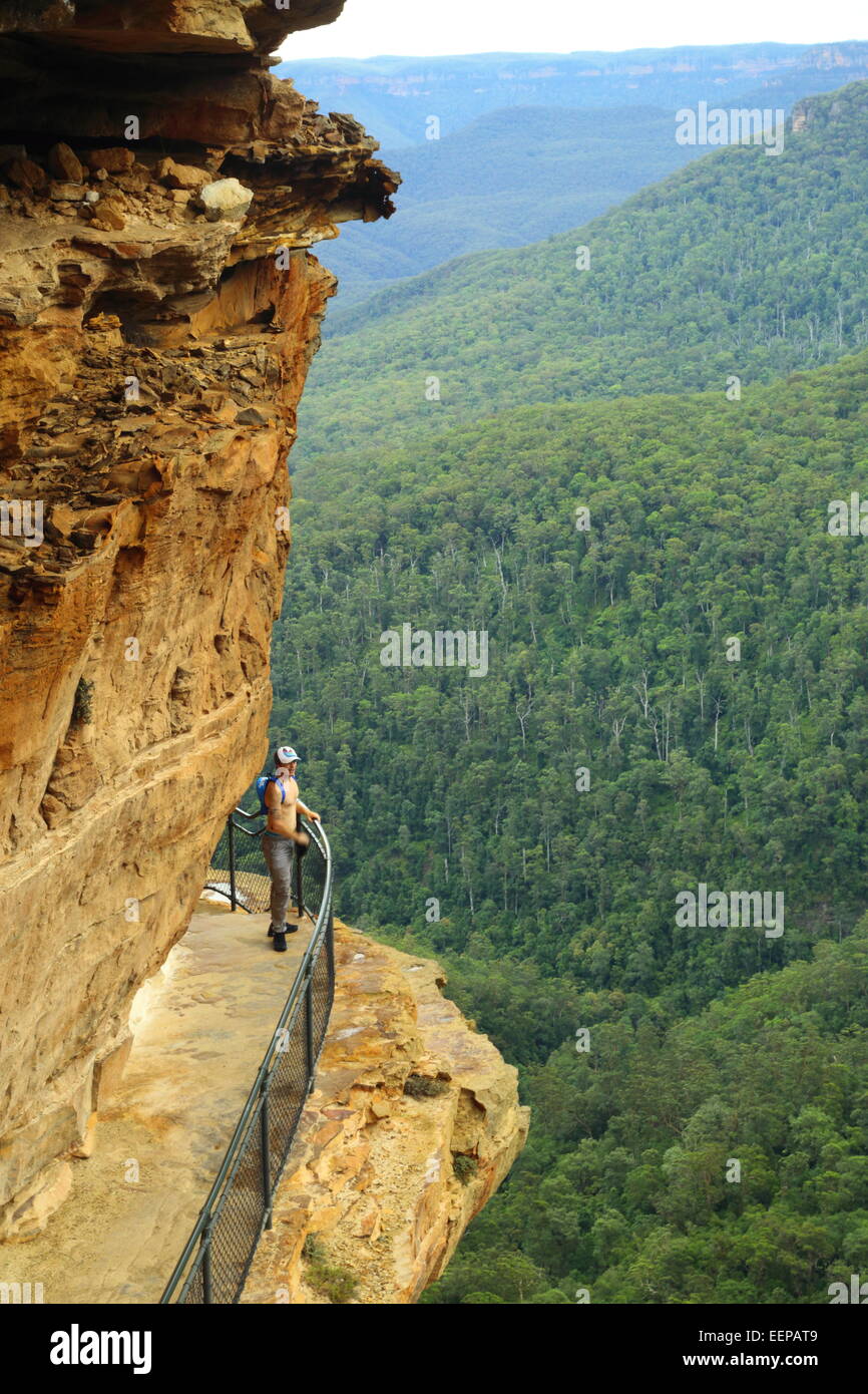 Un maschio di escursionista appoggia e gode della vista di Wentworth Falls dal National Pass nelle Blue Mountains, vicino a Sydney in Australia. Foto Stock