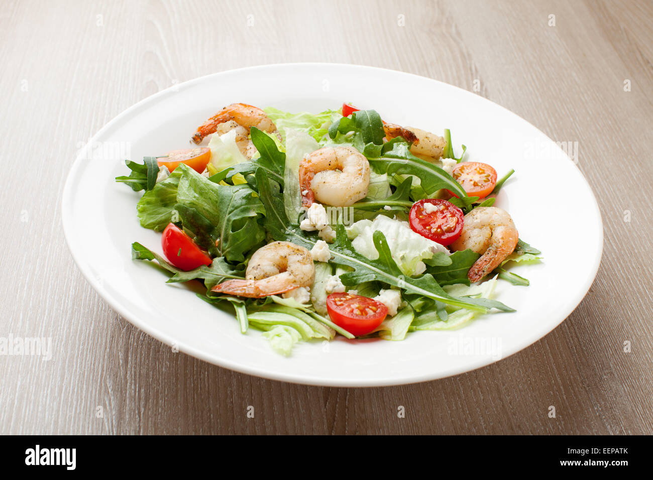 Gourmet freschi frutti di mare con insalata di lattuga, rucola e mais verde, gamberi, pomodori ciliegini, formaggio servita nella piastra bianca Foto Stock