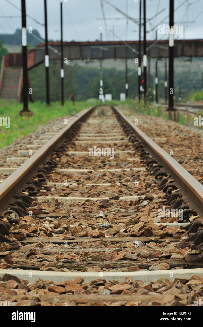 I binari ferroviari che portano a distanza in cui un ponte pedonale che attraversa la linea, nel lato del paese del KwaZulu-Natal, Sud Africa Foto Stock