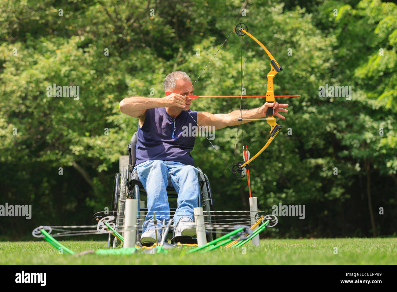 Uomo con lesioni al midollo spinale in carrozzella mirando il suo arco e la freccia per la pratica del tiro con l'arco Foto Stock