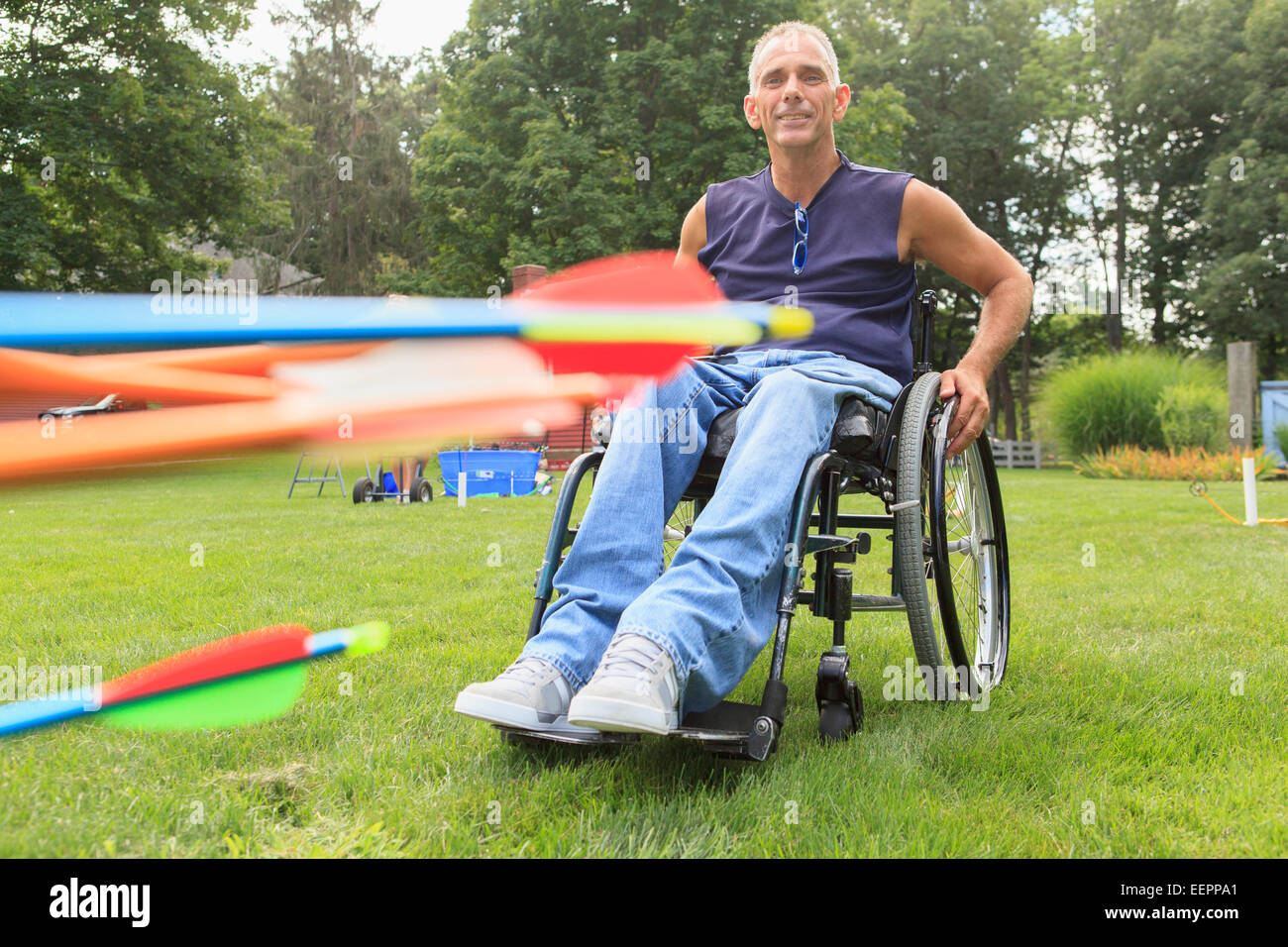 Uomo con lesioni al midollo spinale in sedia a rotelle la preparazione per la pratica del tiro con l'arco Foto Stock