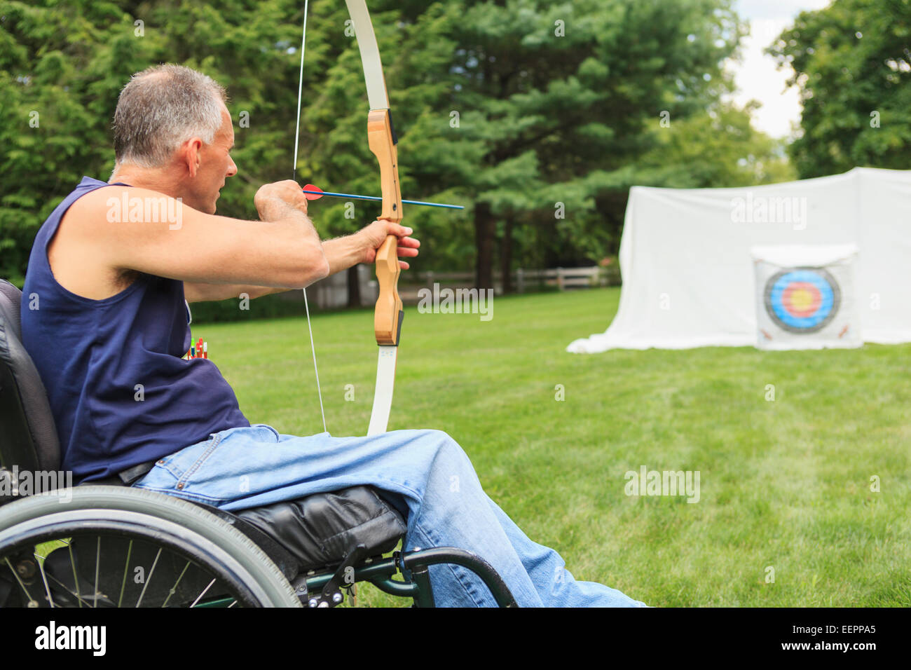 Uomo con lesioni al midollo spinale in carrozzella mirando il suo arco e la freccia per la pratica del tiro con l'arco Foto Stock