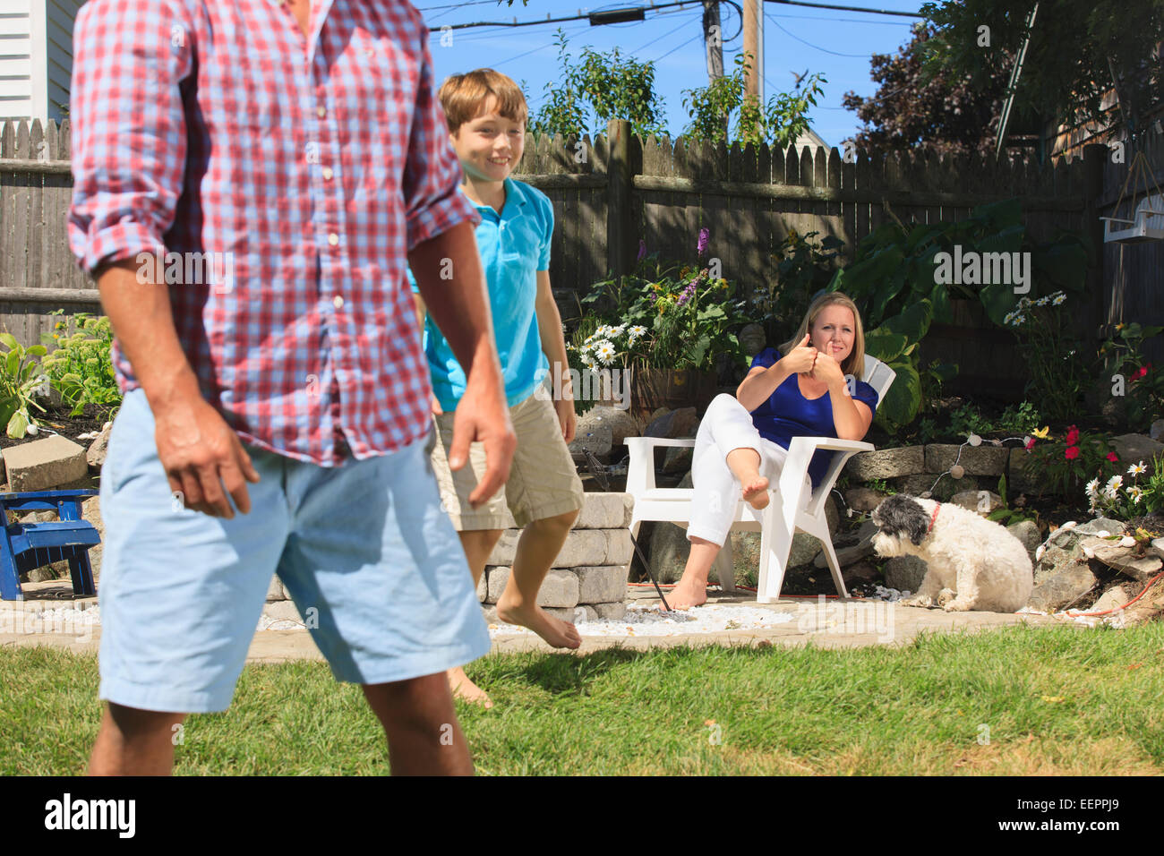 Famiglia con problemi di udito a giocare il gioco del calcio e la firma in American Sign Language in cortile Foto Stock