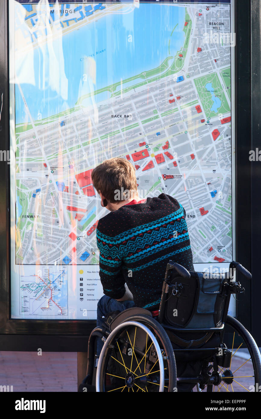 Alla moda uomo con una lesione del midollo spinale in carrozzella guardando una mappa della metropolitana della città Foto Stock