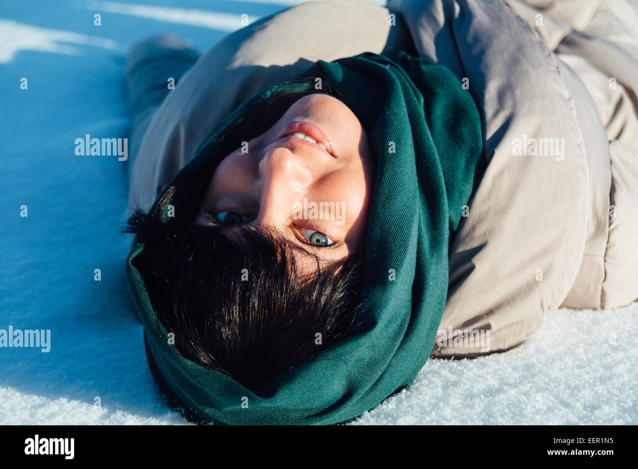 Ragazza distesa sulla neve e sorridente Foto Stock