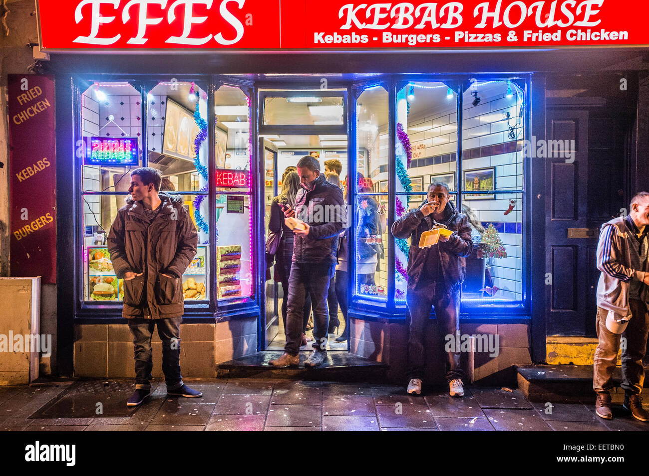 Persone in Aberystwyth al di fuori di una casa di kebab shop negozio di alimentari mangiare take-away cibo la sera tardi dopo aver festeggiato il 2015 anno nuovo. Regno Unito Foto Stock