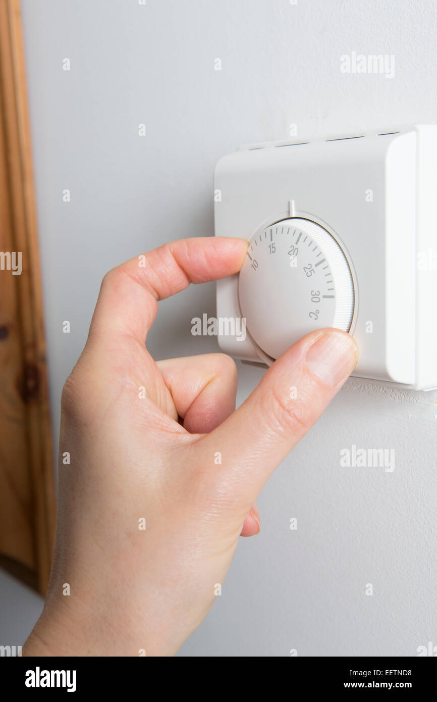 Stretta di mano femminile sul riscaldamento del termostato Foto Stock