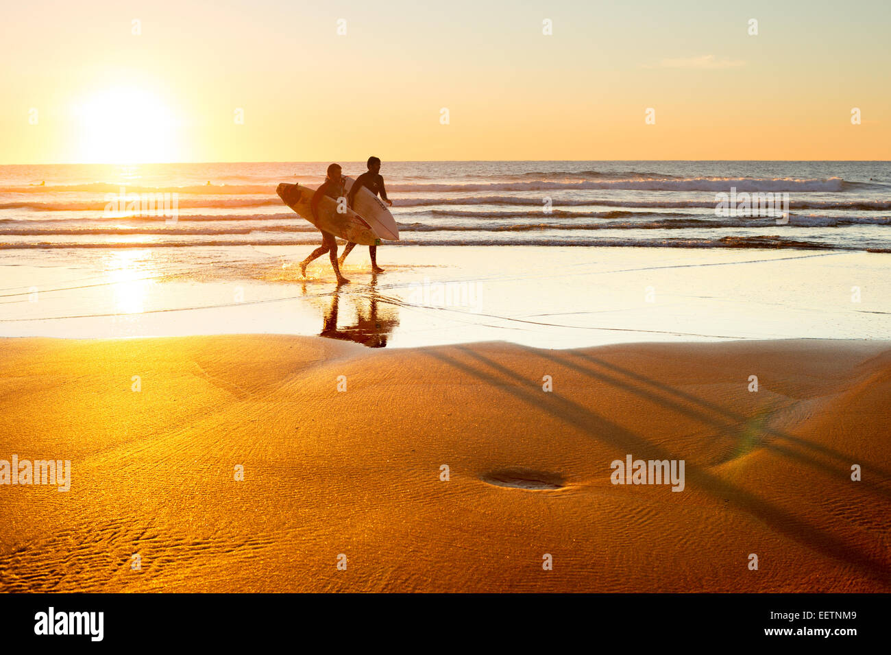 Due surfer correre sulla spiaggia al tramonto. Il Portogallo ha uno dei migliori scene di surf in Europ Foto Stock