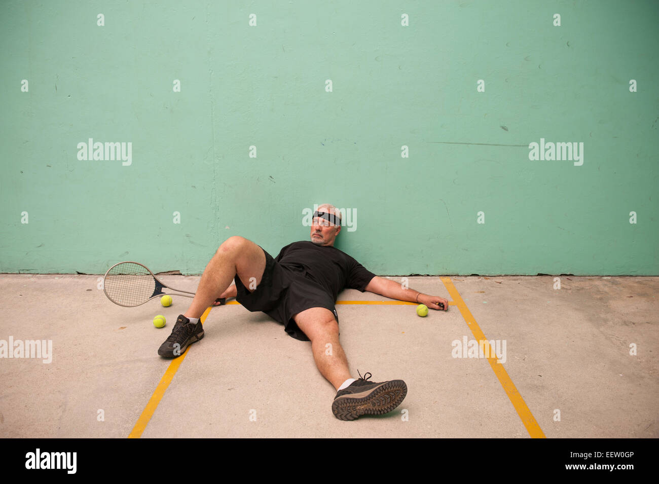 Maschio maturo di perdere a raquetball sul pavimento Foto Stock